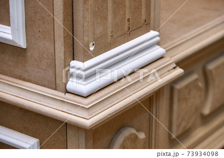 Joinery. Mdf cabinet carcass with moldings and carved base. Wooden furniture manufacturing process 73934098