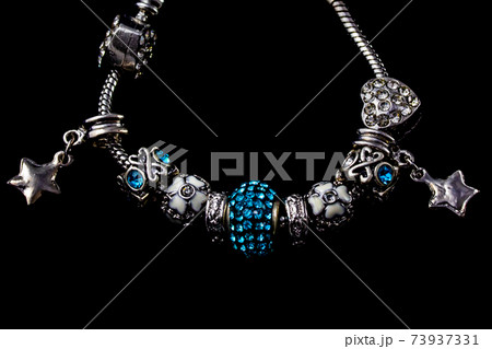 Beautiful bracelet with charms isolated on black background Beautiful bracelet with charms isolated on black background 73937331