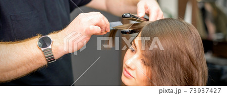 Hairdresser is straightening the hair 73937427
