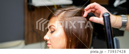 Hairdresser is straightening the hair 73937428