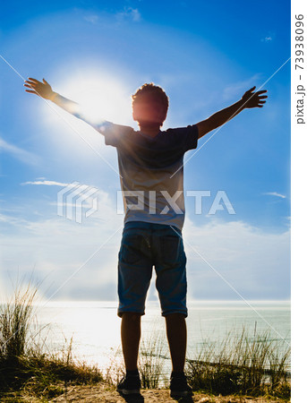 Netherlands, weastkapelle. North sea landscape. A Caucasian boy is inspired by nature and raises his arms to the sky. 73938096