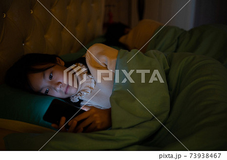 Asian child girl watch movie on smartphone in bedroom,female teenage lying in bed at night time and playing game or chatting on mobile phone,addict social networks,technology,communication concept Asian child girl watch movie on smartphone in bedroom,female teenage lying in bed at night time and playing game or chatting on mobile phone,addict social networks,technology,communication concept 73938467