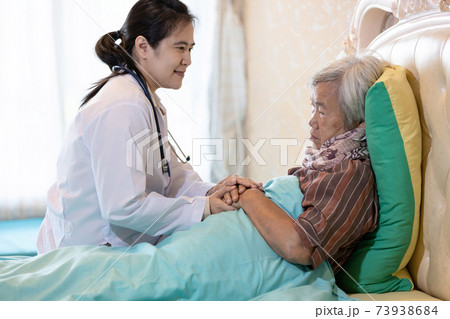 Elderly mother with depressive symptoms or Alzheimer woman feel sad asian female doctor or daughter holding elderly patient hand comforting support in bedroom at home health care depression concept 73938684
