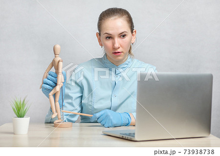 Doctor traumatologist conduct an online video call lesson through a laptop. Doctor traumatologist conduct an online video call lesson through a laptop. 73938738