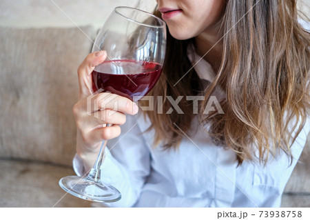 Drunk girl drinks wine from a glass on the couch. Drunk girl drinks wine from a glass on the couch. 73938758