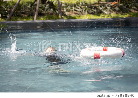 Asian child girl struggling for a life buoy in swimming pool to rescue drowning in dangerous situation in summer vacation, lifebuoy or ringbuoy equipment for save life in water, concept of safety 73938940