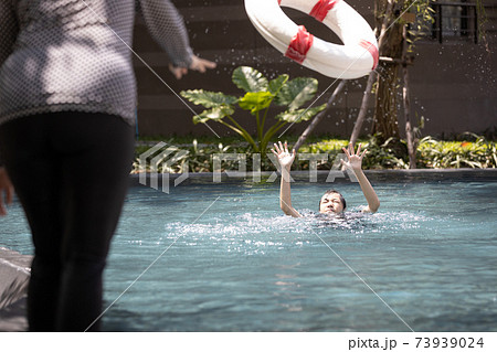 Mother is saving the life of a teenager daughter using ringbuoy to rescue drowning in dangerous situation; asian child girl struggling; asking for help in water; female people throwing lifebuoy help w 73939024