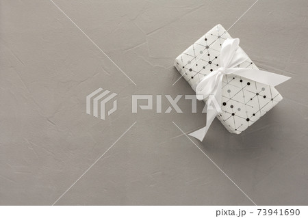 Gift box with a bow on a gray concrete background 73941690