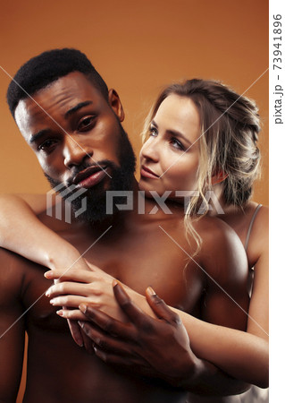 Young pretty couple diverse races together posing sensitive on brown background, lifestyle people concept Young pretty couple diverse races together posing sensitive on brown background, lifestyle people concept 73941896