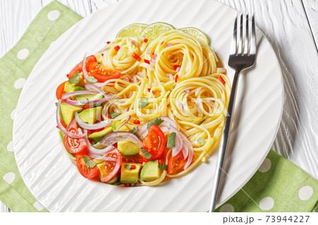 pasta with avocado, tomatoes and lime, top view 73944227