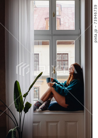 Woman sitting on the big windowsill Woman sitting on the big windowsill 73946739