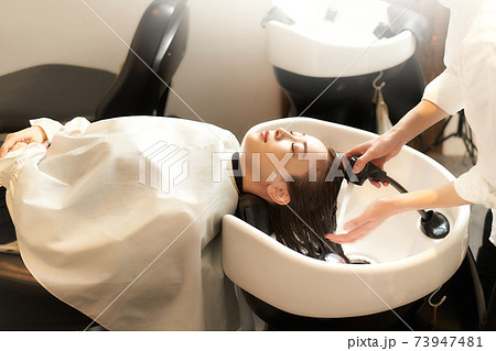 美容室にて洗髪をしてもらう若い女性 73947481
