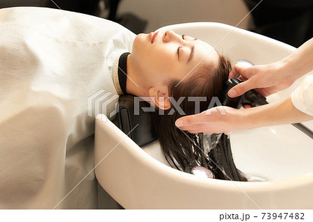 美容室にて洗髪をしてもらう若い女性 73947482