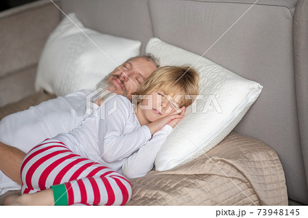Child with dad sleeping on bed during day 73948145