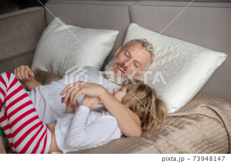 Man hugging child lying on bed Man hugging child lying on bed 73948147