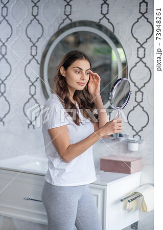 Young woman looking at the small mirror Young woman looking at the small mirror 73948261