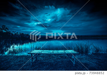 bamboo litter on grass in front of lake and moonlight behind a cloudy at night time bamboo litter on grass in front of lake and moonlight behind a cloudy at night time 73948852
