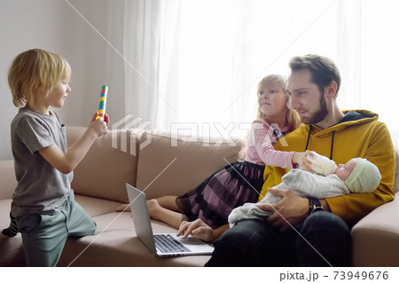 Tired freelancer father with his three kids during quarantine. Home office and household Tired freelancer father with his three kids during quarantine. Home office and household 73949676