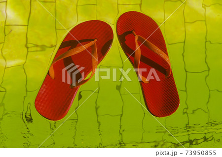 red flip-flops floating in a pool of yellow water, top view red flip-flops floating in a pool of yellow water, top view 73950855