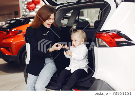 Elegant woman with little daughter in a car salon Elegant woman with little daughter in a car salon 73951151