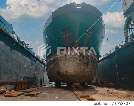 Industry view - Ocean Vessel in the dry dock in shipyard. Old rusty ship under repair 73958383
