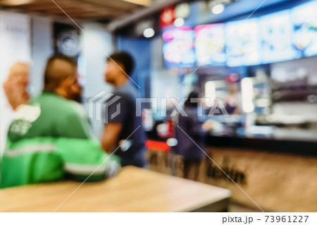 Lens Blurred image of people queueing to see and ordering food items in front of the counter selling fried chicken and hamburger that the sales staff took the fried chicken to the plate in the city. Lens Blurred image of people queueing to see and ordering food items in front of the counter selling fried chicken and hamburger that the sales staff took the fried chicken to the plate in the city. 73961227