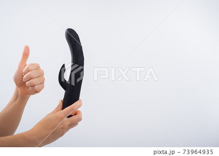 Faceless woman holding black dildo with clitoris stimulator on white background Faceless woman holding black dildo with clitoris stimulator on white background 73964935