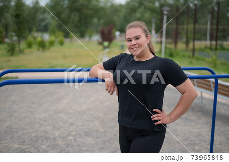 Fat young woman posing by the uneven bars outdoors. Fat young woman posing by the uneven bars outdoors. 73965848