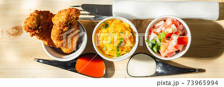 Breaded and herbed chicken breast fillet served with mash potatoes and tomato with onions 73965994