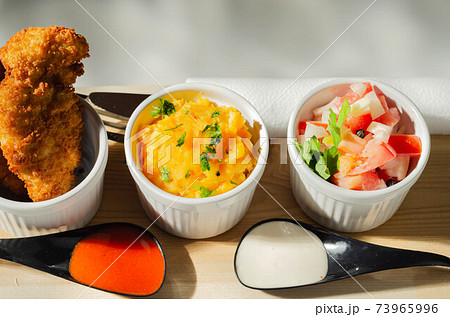 Breaded and herbed chicken breast fillet served with mash potatoes and tomato with onions Breaded and herbed chicken breast fillet served with mash potatoes and tomato with onions 73965996