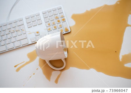 Spilled black coffee on a computer keyboard at a white table Spilled black coffee on a computer keyboard at a white table 73966047