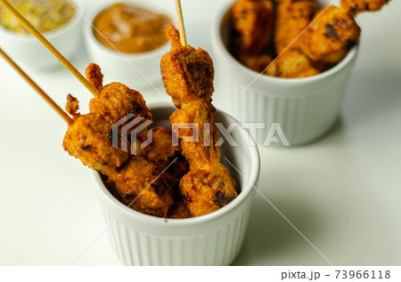 Satay chicken breast marinated in Indonesian style spices and grill on wooden skewers with dip peanut, ketchup, mustard Satay chicken breast marinated in Indonesian style spices and grill on wooden skewers with dip peanut, ketchup, mustard 73966118