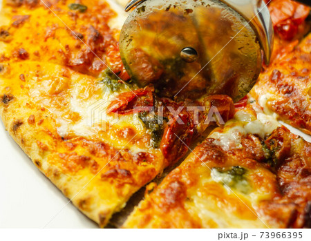 Cutting famous Neapolitan pizza based on buffalo mozzarella and tomatoes with a pizza cutter Cutting famous Neapolitan pizza based on buffalo mozzarella and tomatoes with a pizza cutter 73966395