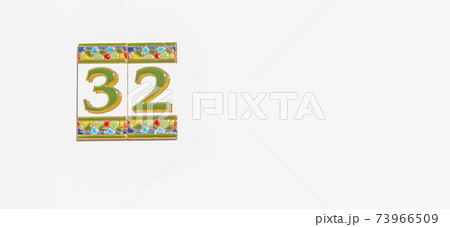 Decorative ceramic house number 32 tile on the wall, characteristic decorative element 73966509