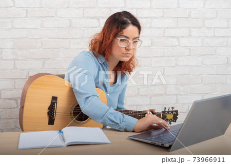 A woman is learning to play the guitar online. Remote music lesson A woman is learning to play the guitar online. Remote music lesson 73966911