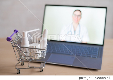 Online doctor. Medical worker at a remote consultation. A computer application for the purchase of medicines in a pharmacy with home delivery. Pharmacist on laptop screen and trolley full of drugs. 73966971