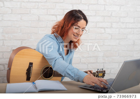 A woman is learning to play the guitar online. Remote music lesson A woman is learning to play the guitar online. Remote music lesson 73966973