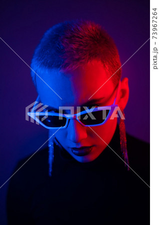 Portrait of a young woman with a short male haircut in sunglasses in neon light in the studio 73967264