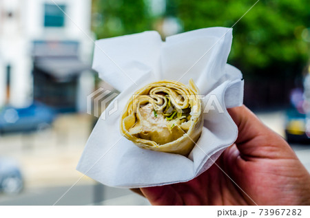 Chicken breast with caesar dressing and lettuce in a gluten-free tortilla wrap in the hand 73967282