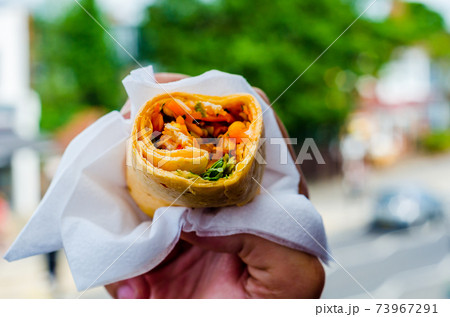 Chicken breast with piri piri sauce and lettuce in a chili tortilla wrap in the hand Chicken breast with piri piri sauce and lettuce in a chili tortilla wrap in the hand 73967291