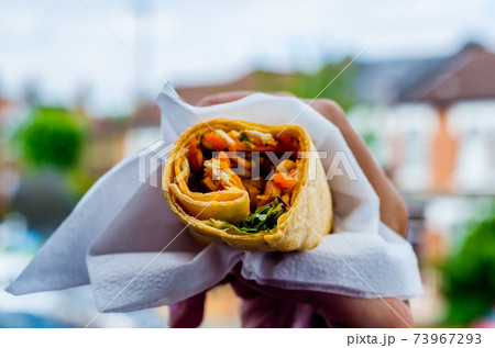 Chicken breast with piri piri sauce and lettuce in a chili tortilla wrap in the hand Chicken breast with piri piri sauce and lettuce in a chili tortilla wrap in the hand 73967293