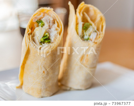 Chicken breast with caesar dressing and lettuce in a gluten-free tortilla wrap 73967377
