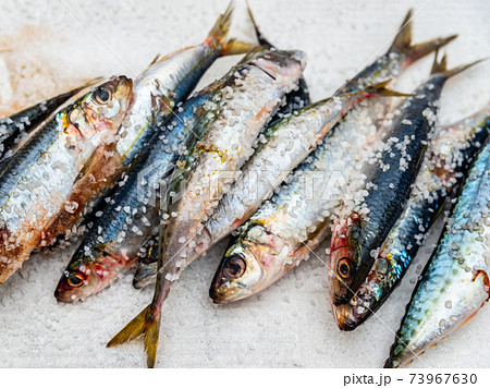 Whole raw organic mackerel fish with sea salt lying on a flat surface 73967630