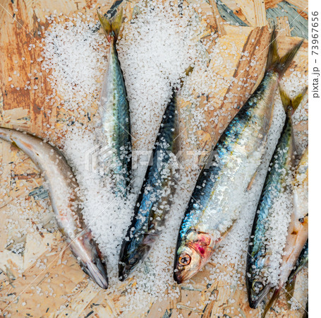 Whole raw organic mackerel fish with sea salt lying on a flat surface 73967656