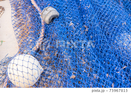 Industrial Fishing Equipment Fishnets and Fishing Lines lying on concrete in the port 73967813