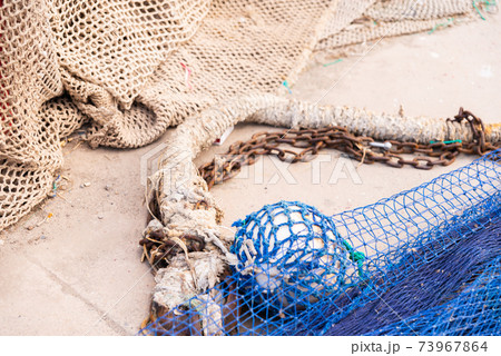 Industrial Fishing Equipment Fishnets and Fishing Lines lying on concrete in the port 73967864