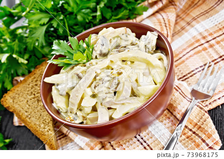 Salad with squid and champignons in bowl on napkin 73968175