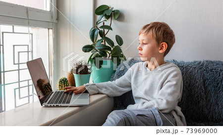 Little school boy having video call, online class on laptop during covid quarantine lockdown. 73969000