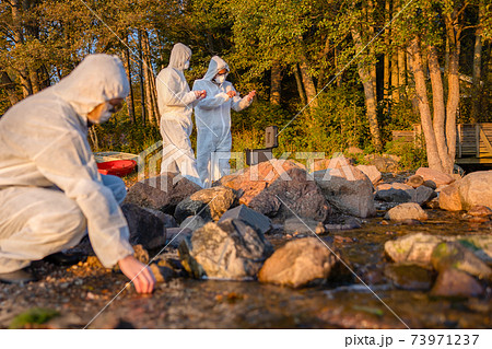 Team of researchers analyzing water sample at seashore Team of researchers analyzing water sample at seashore 73971237