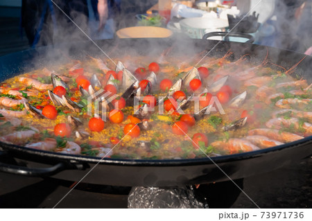Cooked paella with shrimp, musse, rice, cherry tomato in huge pan - close up Cooked paella with shrimp, musse, rice, cherry tomato in huge pan - close up 73971736